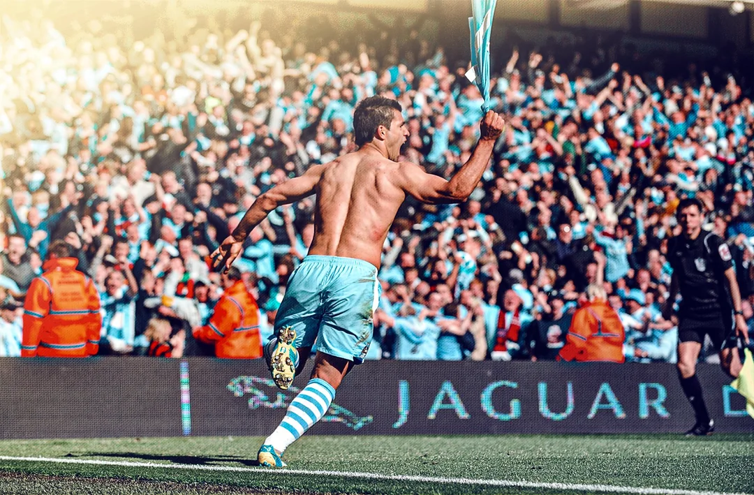 A footballer celebrates a goal in front of a packed stadium